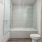 Bathroom with glass shower/tub combo, toilet, and brown cabinets