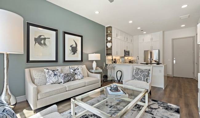Living room with couch and lounge chair with big window overlooking courtyard