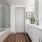Bathroom with white cabinets, double vanity sinks, and glass shower/tub combo